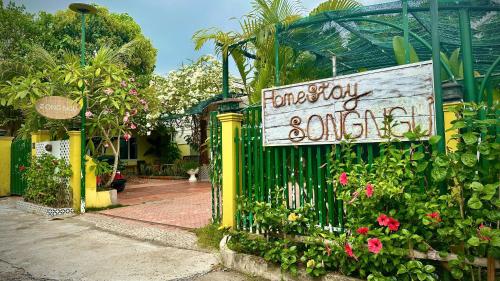 a sign on a gate in a garden with flowers at Song Ngư Riverside Homestay in Can Tho