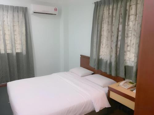 a bedroom with a white bed and a window at Hotel O Asia City in Kota Kinabalu