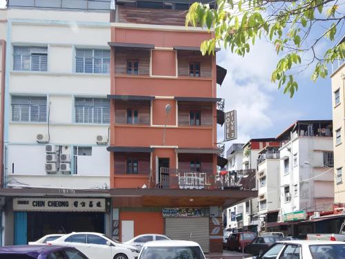 a tall orange building on a city street with cars at Hotel O Five 2 in Kota Kinabalu
