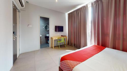 a bedroom with a bed and a desk and a window at Yootel Boutique Hotel in Kajang