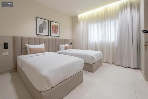 a hotel room with two beds and a window at Prime Residence Zayed Heights in Sheikh Zayed