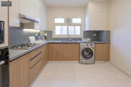 a kitchen with a washing machine and a sink at Prime Residence Zayed Heights in Sheikh Zayed