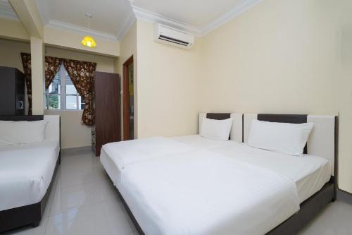two beds in a room with white walls at Hotel O Bangi Sri Minang Guesthouse in Bangi