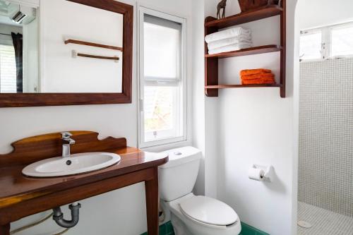 a bathroom with a toilet and a sink and a window at Plantation House Trinidad suite in Playa del Carmen