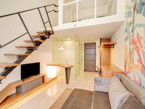 a living room with a couch and a tv and a staircase at Collection O 30 Amega Crown Sub in Surabaya