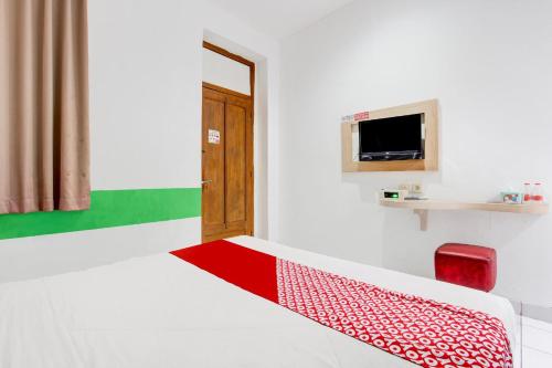 a room with a bed and a chair and a television at Collection O Jalan Slamet Riyadi Near Kampung Batik Kauman Formerly Hotel Grand Kota in Solo