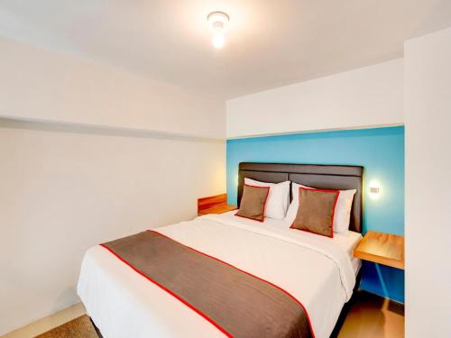 a bedroom with a large bed with a blue wall at Collection O 30 Amega Crown Sub in Surabaya