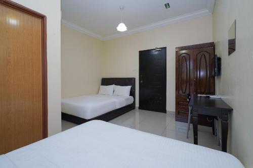 a bedroom with a bed and a desk and a bed at Hotel O Bangi Sri Minang Guesthouse in Bangi
