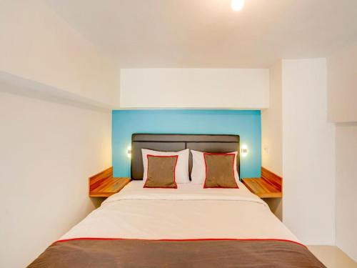 a bedroom with a large bed with a blue headboard at Collection O 30 Amega Crown Sub in Surabaya