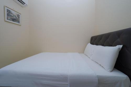 a white bed with a black headboard and white pillows at Hotel O Bangi Sri Minang Guesthouse in Bangi