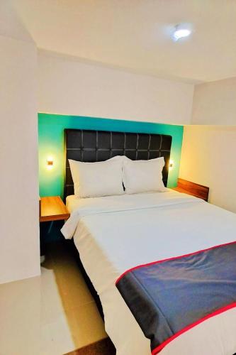 a bedroom with a large bed with a green headboard at Collection O 30 Amega Crown Sub in Surabaya