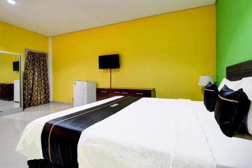 a bedroom with a white bed and a yellow wall at Hotel O Jalan Slamet Riyadi Near Bandara Adi Soemarmo Formerly Amanah Sejahtera in Solo