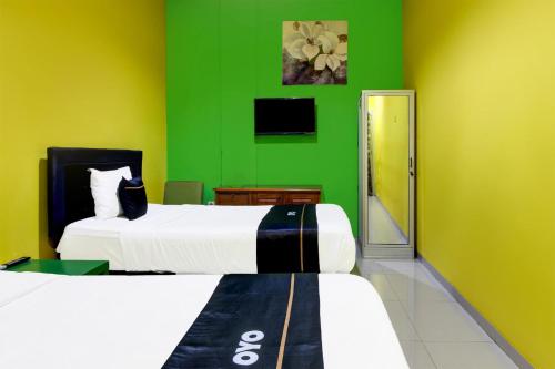 a green room with two beds and a green wall at Hotel O Jalan Slamet Riyadi Near Bandara Adi Soemarmo Formerly Amanah Sejahtera in Solo