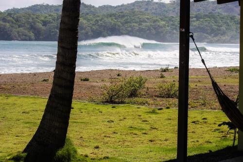 a hammock in front of a beach with the ocean at Beach Break Hotel & Surf Camp de Playa Venao in Playa Venao