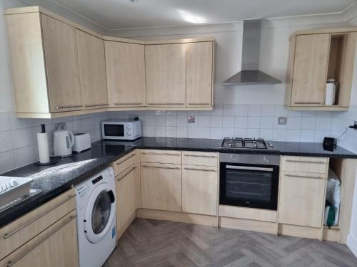 a kitchen with wooden cabinets and a washer and dryer at Dunstans Retreat in Canterbury