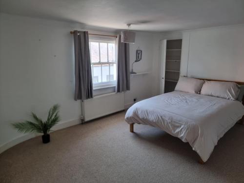a white bedroom with a bed and a window at Dunstans Retreat in Canterbury