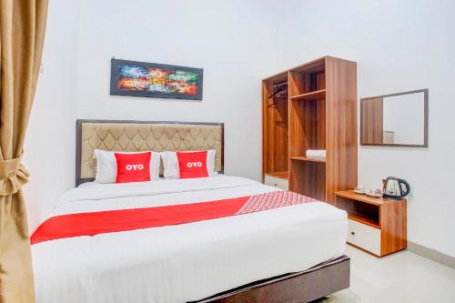 a bedroom with a large bed with red pillows at Hotel O Sukarame Near Imanuel Hospital Way Halim Formerly Hotel Griya Bawean in Bandar Lampung