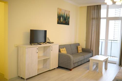 a living room with a couch and a flat screen tv at Cozy Apartment Near The Beach in Kakhaberi