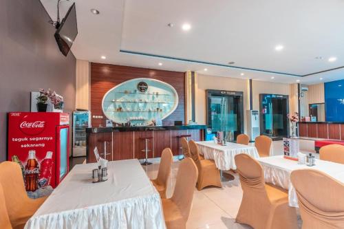 a restaurant with white tables and chairs and a bar at Collection O Hotel Igloo in Bekasi