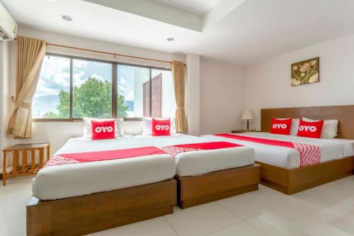 2 camas en un dormitorio con almohadas rojas y blancas en Super OYO 1096 Winner Inn Hotel, en Chiang Mai