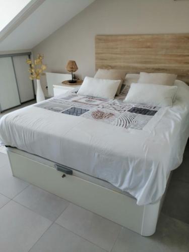 un grand lit blanc avec des draps et des oreillers blancs dans l'établissement Cap sur l'océan, à Saint-Brévin-les-Pins