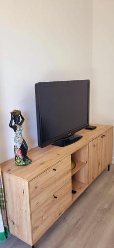 une télévision au-dessus d'un centre de divertissement en bois dans l'établissement The Driant beach is 50m and 150m from the center, au Grau-du-Roi