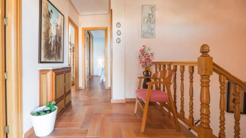 a hallway with a wooden staircase with a chair and a stair case at Casa Espada Tizona by Toledo AP in Bargas