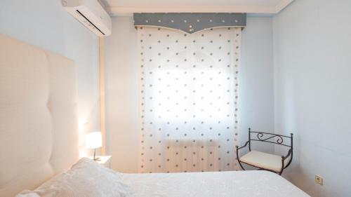 a bedroom with a bed and a window with a chair at Casa Espada Tizona by Toledo AP in Bargas