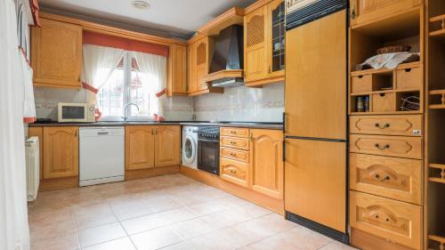 a kitchen with wooden cabinets and a washer and dryer at Casa Espada Tizona by Toledo AP in Bargas