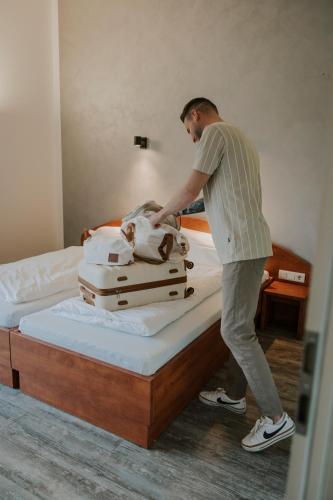 a man standing on a bed with a stack of luggage at Haus am See - Gochness in Kessel