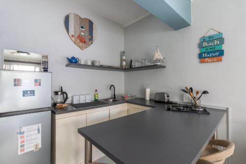 a kitchen with a black counter top and a refrigerator at Hartenbos Breakaway - LightHouse Cottage in Mossel Bay