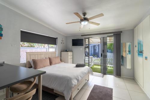a bedroom with a bed and a ceiling fan at Hartenbos Breakaway - LightHouse Cottage in Mossel Bay