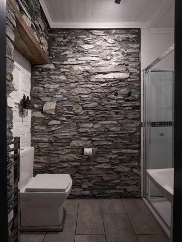 a bathroom with a stone wall with a toilet and a shower at Cambridge House in Windermere