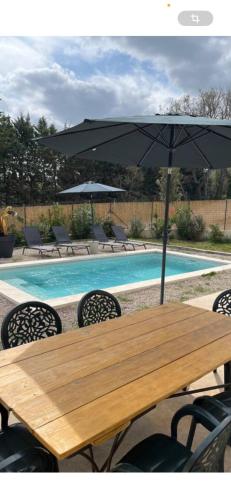 a wooden table with an umbrella next to a pool at Bastide 3 chambres 6personnes avec piscine sur Aix en Provence in Aix-en-Provence