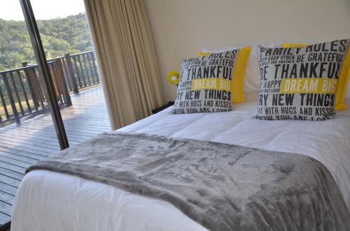 a bedroom with a bed with pillows and a balcony at River Kaya in Kromriviermond