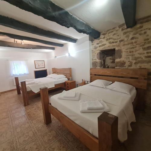 une chambre avec deux lits et un mur en pierre dans l'établissement Mas de Mandirac, à Varen