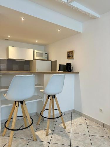 2 chaises blanches assises à côté d'un comptoir de cuisine dans l'établissement La Tannière - 4 à 6 personnes - Lit KingSize - Proche Gare, à Nancy