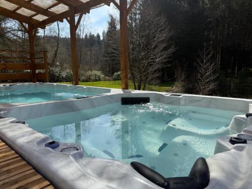 a large hot tub in a backyard with a wooden deck at L'écrin de la forêt in Jeanménil