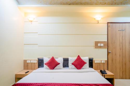 a bedroom with a bed with red pillows at Mahadev Regency Hotel in Jaipur
