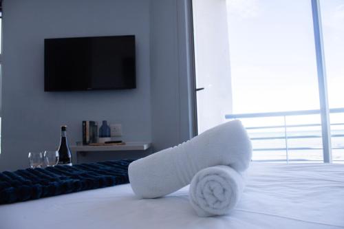 a bedroom with a white bed with a tv on the wall at Ocean Breeze Hotel in Strand