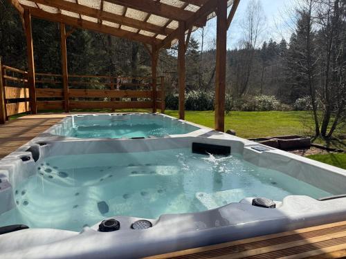 a hot tub on a deck with a pergola at L'écrin de la forêt in Jeanménil