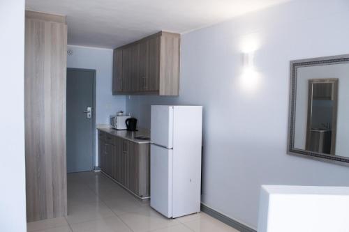 a kitchen with a white refrigerator and a mirror at Ocean Breeze Hotel in Strand