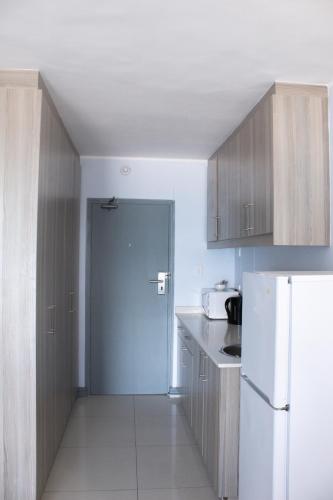 a kitchen with a white refrigerator and wooden cabinets at Ocean Breeze Hotel in Strand