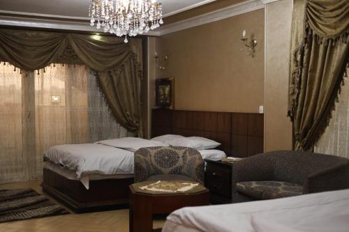 a bedroom with two beds and a chair and a chandelier at Royal palace in Kafr ‘Işām
