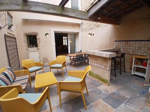 an outdoor patio with chairs and tables and a piano at Pierres anciennes et soirées douces Coeur de ville in Pézenas