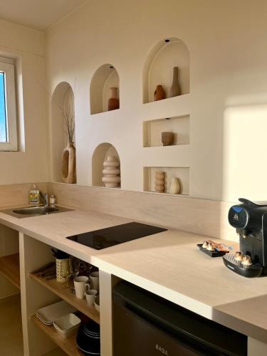 une cuisine avec un comptoir et des étagères avec des vases dans l'établissement La Suite Balinaise, vue mer et dunes - MALO'Cation, à Dunkerque