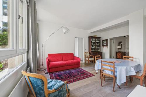 un salon avec une chaise rouge et une table dans l'établissement Branly - Franco Russe 1bdr B'Your Home, à Paris