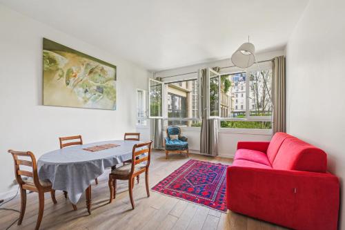 un salon avec une table et un canapé rouge dans l'établissement Branly - Franco Russe 1bdr B'Your Home, à Paris