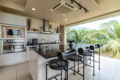 a kitchen with a island with bar stools at White Monkey Villa - Private Pool & Jacuzzi in Pantai Cenang