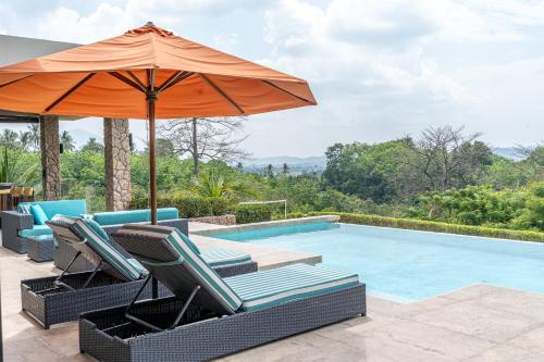 an orange umbrella and chairs next to a swimming pool at White Monkey Villa - Private Pool & Jacuzzi in Pantai Cenang